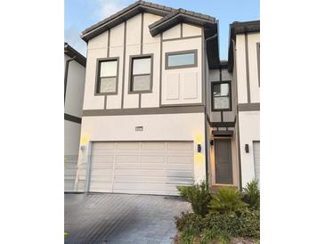 Charming two-story townhome featuring a two-car garage, manicured landscaping, and modern architectural details at 10437 Ebb Tide Ln, Orlando, FL 32821