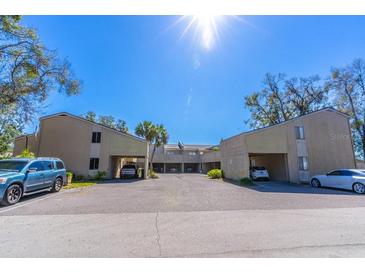 A daytime exterior view of a charming two-story condo building with covered parking and lush landscaping at 1428 Oak Pl # J, Apopka, FL 32712