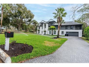 View of the home's exterior with a well-manicured lawn, sprinkler system, and paver driveway at 2721 Ingeborg Ct, Windermere, FL 34786