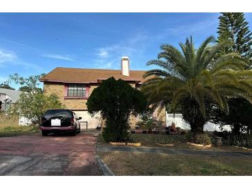 Two-story brick home with mature landscaping, pink trim, and a driveway with a parked vehicle at 3336 Pell Mell Dr, Orlando, FL 32818