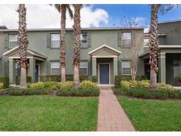 Charming townhome features manicured landscaping, palm trees, and a welcoming brick pathway to the front door at 14849 Driftwater Dr, Winter Garden, FL 34787