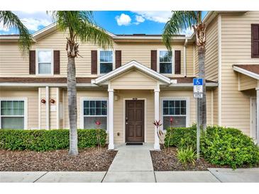 Inviting tan-colored townhome featuring a covered entrance, neatly trimmed bushes, and two towering palm trees at 3204 Gold Ln, Kissimmee, FL 34747