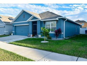 Charming single-story home features blue siding, a well-manicured lawn, and an attached garage at 756 Kindred Ln, Auburndale, FL 33823