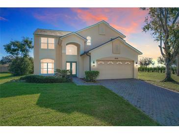 Two story home featuring an arched entryway, attached two car garage, and manicured landscaping at 8438 Diamond Cove Cir, Orlando, FL 32836