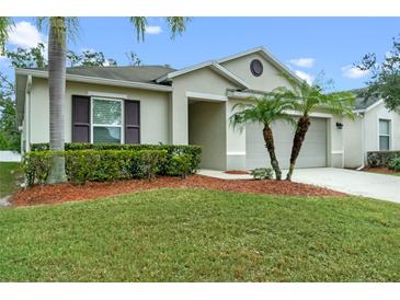 Charming single-story home with a well-maintained lawn, palm trees, and a two-car garage at 921 Emerald Green Ct, Kissimmee, FL 34746