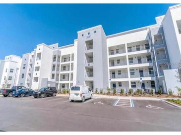 Modern condo building featuring multiple floors with balconies and ample parking at 3121 Paradox Cir # 203, Kissimmee, FL 34746