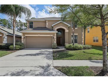 Charming two-story home featuring a well-manicured lawn, mature trees, and a two-car garage at 620 Orange Cosmos Blvd, Davenport, FL 33837