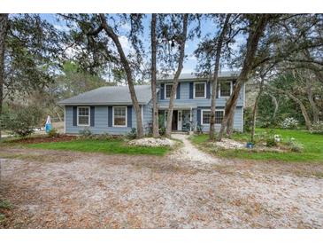 Charming two-story home with blue siding, complemented by a beautifully landscaped front yard and mature trees at 1797 Whispering Forest Trl, Chuluota, FL 32766