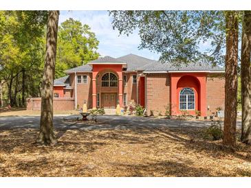 Elegant brick home boasts a striking arched entryway, manicured landscaping, and a circular driveway at 19715 Eaglesview Cir, Umatilla, FL 32784