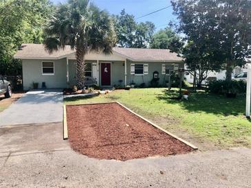Charming single-story home with a well-maintained front yard, mature landscaping, and a cozy bench by the front door at 32804 Blossom Ln, Leesburg, FL 34788