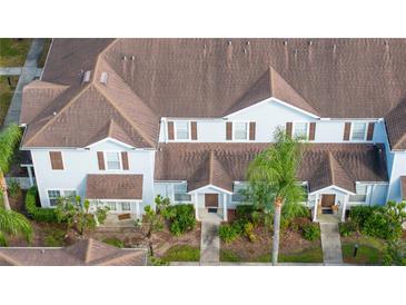 Aerial view of light blue townhomes with brown shutters and roofs surrounded by sidewalks and green landscaping at 5354 Diplomat Ct # 106, Kissimmee, FL 34746