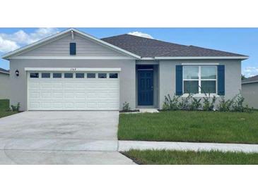 Charming single-story home features a gray exterior, attached two car garage, and well-manicured lawn at 2926 Reggae Pl, Haines City, FL 33844