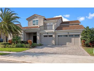 Elegant two-story home with stone accents, balcony, three-car garage, and lush landscaping at 10912 Mobberley Cir, Orlando, FL 32832