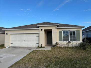Charming single-story home featuring a two-car garage, landscaped yard, and neutral-colored exterior at 1463 Riverboat Dr, Kissimmee, FL 34744