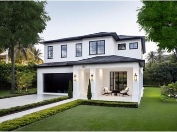 Beautiful two-story home featuring a manicured lawn, black framed windows, and a covered front porch with seating area at 1917 Geigel Ave, Orlando, FL 32806