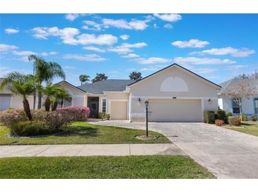 Charming home with a lush front yard, featuring mature palms and well-maintained landscaping and a paved driveway at 25221 Quail Croft Pl, Leesburg, FL 34748