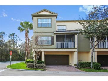 Three-story townhome with a two-car garage, mature landscaping, and a screened-in porch at 2604 Grand Central Pkwy # 12, Orlando, FL 32839