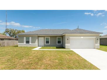Inviting single-story home featuring a two-car garage, well-maintained lawn, and neutral color palette at 2765 Sw 140Th Pl, Ocala, FL 34473