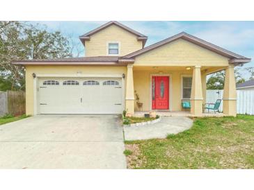 Inviting yellow two-story home featuring a bright red front door and attached one car garage at 410 South Hudson St, Orlando, FL 32835