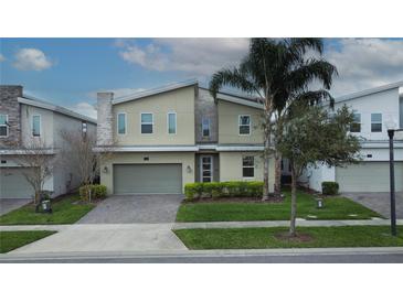 Modern two-story home with a two-car garage, stone accents, tidy landscaping, and a well-manicured front lawn at 561 Pebble Beach Dr, Davenport, FL 33896