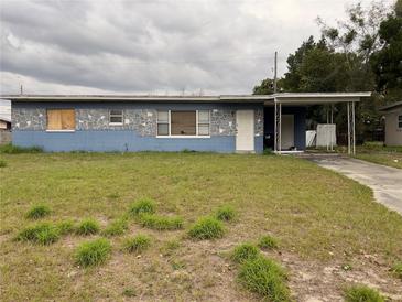 A single-story home with a blue exterior, a covered carport, and an overgrown front lawn at 1606 26Th St, Orlando, FL 32805