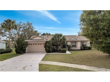 Charming single-story home with a well-manicured lawn, mature trees, and a two-car garage at 1739 Nectarine Trl, Clermont, FL 34714