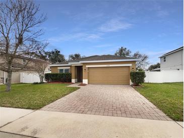 Charming one-story home featuring manicured landscaping and a brick paver driveway at 240 Whispering Pines Way, Davenport, FL 33837