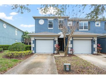 Blue two-story townhome featuring a single-car garage and well-maintained front yard with attractive landscaping at 3575 Victoria Pines Dr # 276, Orlando, FL 32829