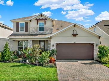 Charming two-story home featuring stone accents, a well-manicured lawn, and a brick-paved driveway at 565 Big Pine Ave, Minneola, FL 34715