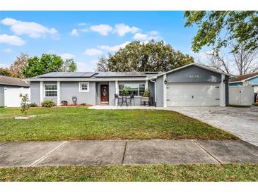 Charming single-story home with well-manicured lawn, solar panels and cozy front patio seating area at 9729 Heatherwood Ct, Orlando, FL 32825