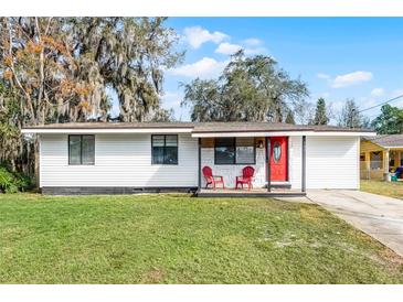Charming single-story home with a bright red door and cozy front porch seating at 144 Delespine Dr, Debary, FL 32713