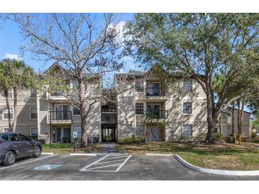 Inviting condo with a tan exterior, mature trees, and convenient parking at 1948 Lake Atriums Cir # 129, Orlando, FL 32839