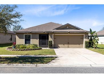 Inviting single-story home with a well-manicured lawn and a two-car garage at 2491 Bracknell Forest Trl, Tavares, FL 32778