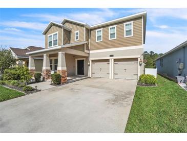 Two-story home featuring a two-car garage and a well-manicured front lawn at 3128 Dark Sky Dr, Harmony, FL 34773