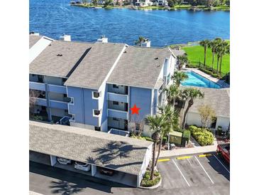 Three-story condo with a covered parking area, palm trees, and a pool on a body of water at 4117 Fairview Vista Pt # 206, Orlando, FL 32804