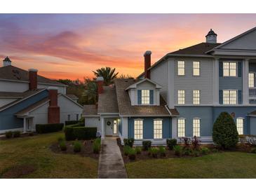 Charming two-story townhome featuring a beautifully landscaped front yard and inviting entrance at sunset at 7691 Heritage Crossing Way # C-1, Reunion, FL 34747