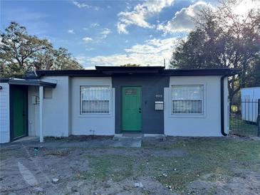 Charming single-story home features a gray and white facade and a lovely green front door at 803 N Pine Hills Rd, Orlando, FL 32808