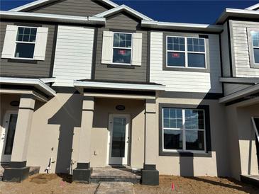 New two-story townhome features a light beige stucco facade, large windows and gray and white trim at 9356 Bolshoi Aly, Winter Garden, FL 34787