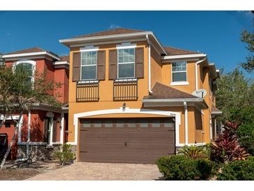 Charming two-story home with a brick driveway, brown shutters, and a two-car garage at 9575 Silver Buttonwood St, Orlando, FL 32832