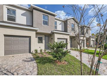 Charming townhome featuring a gray exterior, paved driveway, and manicured landscaping at 1209 S Station Pl # 306, Orlando, FL 32809