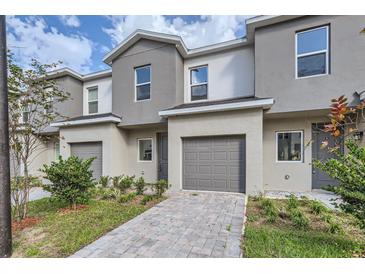 Two-story townhome featuring a one car garage, landscaped front yard, and neutral gray and beige exterior paint at 1217 S Station Pl # 502, Orlando, FL 32809