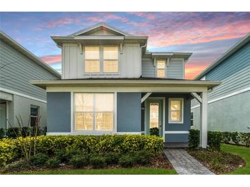 Charming two-story home with a covered entry and lush landscaping at sunset at 14218 Lanikai Beach Dr, Orlando, FL 32827