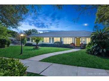 Charming home featuring lush green lawn, vibrant landscaping, and warm lighting at 2368 Summerfield Rd, Winter Park, FL 32792