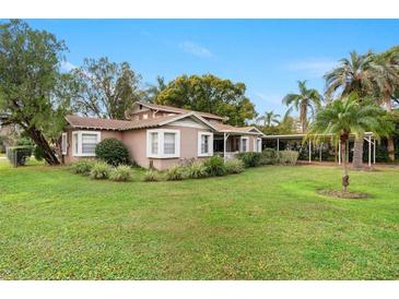 Charming home featuring lush landscaping, mature trees and a convenient covered carport at 26 Backspin Ln, Orlando, FL 32804