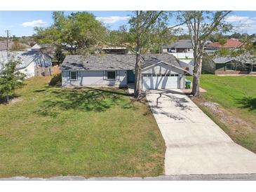 Charming single-story home with a well-manicured lawn and a long driveway leading to a two-car garage at 2801 W Covington Dr, Deltona, FL 32738