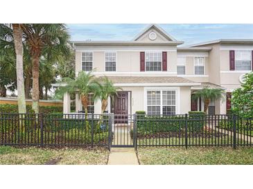 Charming two-story townhouse featuring a black metal fence, lush landscaping, and a welcoming front entrance at 4527 Sunset Ln, Oviedo, FL 32765
