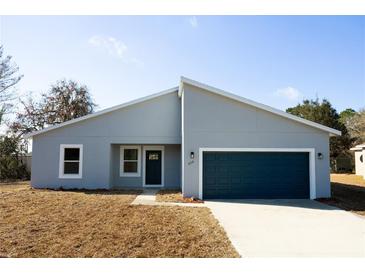 Charming single-story home featuring a blue garage door, modern design, and well-maintained front yard at 656 Marion Oaks Mnr, Ocala, FL 34473