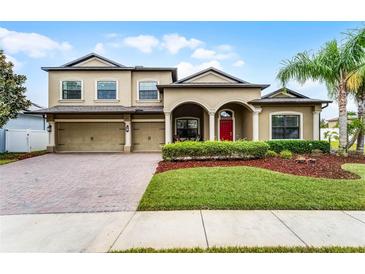 Charming two-story home with a well-manicured lawn, brick driveway, and an inviting red front door at 2829 Autumn Breeze Way, Kissimmee, FL 34744