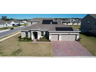 Inviting single-story home featuring a well-manicured lawn, solar panels, and an attached two-car garage at 4897 Gilded Jewel Dr, Mount Dora, FL 32757