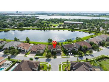 Beautiful aerial view of a lakefront home with lush landscaping and a tile roof at 8231 Chilton Dr, Orlando, FL 32836